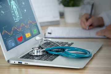 Doctor taking notes in clinic, Stethoscope medical on laptop keyboard. Monitor showing skeleton on computer screen, Health and technology concept.