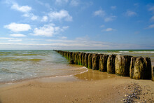 Side View Of An Old Wooden Pier On A Large Bay With Blue Sky In The Background. Baltic Sea Latvia