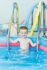 Wall Mural - A 2-year-old little boy learns to swim in a clean pool. Child development. Developmental pool for teaching children to swim. Swimming school