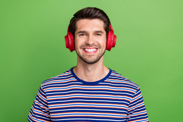 Sticker - Closeup portrait photo of smiling happy youngster guy striped t shirt listen comfort brand new headphones isolated on green color background