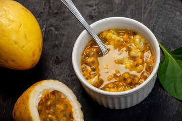 Poster - White ceramic bowl filled to the brim with passion fruit on a black surface