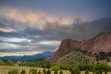 Poster - Stunning nature scene featuring a grassy mountain field lit up by a vibrant orange and pink sunset