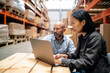 © InputUX - Warehouse managers immersed in work on a laptop, efficiently coordinating logistics, shipping, and inventory for business fulfillment.