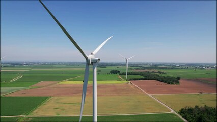 Canvas Print - Drone shot over windmills in a green fields at countrysided under a blue sky