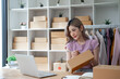 © Wuttichaik - Young woman owner ship business start small business in a cardboard box and calculate price product by calculator and laptop computer