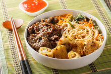 Bun Bo Xao Is A Vietnamese Noodle Salad Made With Marinated Flank Steak, Vermicelli Noodles, Vegetables And Crispy Nem Spring Rolls Closeup On The Table. Horizontal