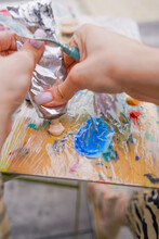 Close-up Of A Girl Artist Squeezing Paint From A Tube Onto A Palette In The Process Of Creating A Painting 