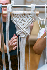 Wall Mural - Woman's delicate hands making white macrame.