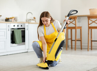 Canvas Print - Young woman with vacuum cleaner in kitchen