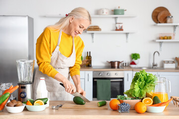 Canvas Print - Mature woman cutting avocado for healthy smoothie in kitchen