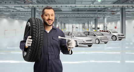 Sticker - Auto mechanic holding a tire on his shoulder and a lug wrench in a car garage