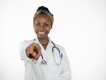 Young Female Doctor Pointing At Camera While Smiling. Looking At Camera Isolated On White Background