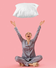 Poster - Young woman in pajamas throwing pillow on pink background