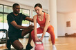 © kegfire - Trainer helping woman doing exercise with kettlebell at gym