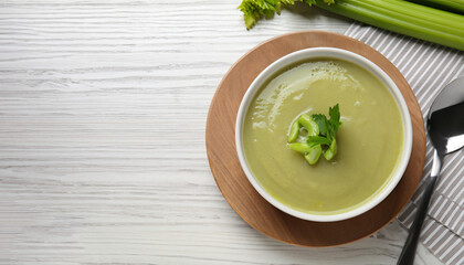 Wall Mural - Bowl of delicious celery soup served on white wooden table, flat lay. Space for text