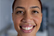 Portrait of happy biracial female doctor with nose piercing in corridor at hospital