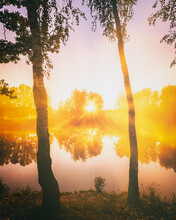 Dawn On A Lake Or River With A Sky Reflected In The Water, Birch Trees On The Shore And The Sunbeams Breaking Through Them And Fog In Autumn. Aesthetics Of Vintage Film.