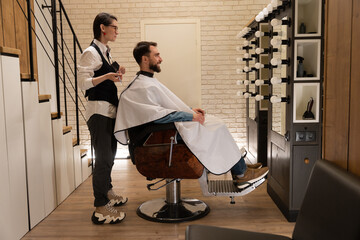 Satisfied client sits in a barbershop in a hairdressing chair