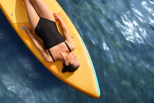 Young Woman Lying On SUP Board In Sea, Top View. Space For Text