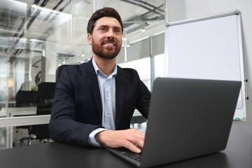 Poster - Man working on laptop at black desk in office