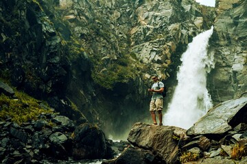 Wall Mural - Men using mobile phone near waterfall in the forest