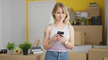 Poster - Young blonde woman using smartphone standing at new home