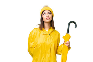 Wall Mural - Young Russian woman with rainproof coat and umbrella over isolated chroma key background and looking up