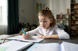 © Mediaphotos - Little boy making notes in copybook at desk, he doing his homework at home