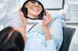 Woman patient lying on orthodontic chair and looking at mirror on her new healthy and white smiles