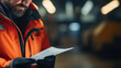© Malika - Man in an orange jacket is reading a sheet of paper at the industrial plant