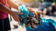 © Malika - Hand holds a recycling bag in front of a bin filled with rubbish