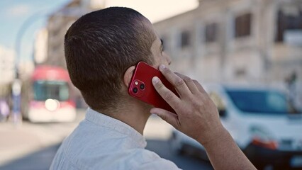 Sticker - Young hispanic man speaking on the phone backwards at street