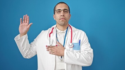 Sticker - Young hispanic man doctor making an oath with hand on chest over isolated blue background