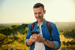 © baranq - Portrait of handsome male backpacker using his smartphone while hiking