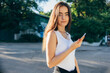 © progressman - Portrait of a young brunette woman using a smartphone outdoors