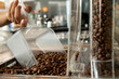 © ADDICTIVE STOCK - Crop person pouring coffee beans from plastic scoop into grinder