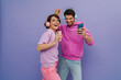 © Drobot Dean - Young couple dancing while listening music with headphones and mobile phones isolated over purple background
