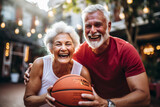 Happy eldery couple playing basketball together in the city. Elderly people and sport concept.