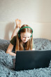 © Анна Молько - a girl in a green t-shirt and green sneakers is working on a laptop on the bed