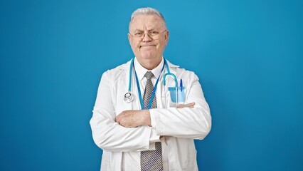 Sticker - Middle age grey-haired man doctor smiling confident standing with arms crossed gesture over isolated blue background