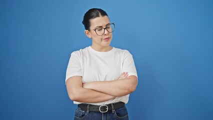 Sticker - Young beautiful hispanic woman with arms crossed looking upset over isolated blue background