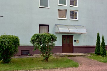 Building with a roof made of polyurethane in front of the entrance and trees for decoration next to the green areas