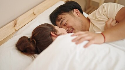 Wall Mural - Man and woman couple lying on bed hugging each other touching nose at bedroom