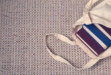 Clever Weighty Books In Textured Blue And Lilac Fabric Covers Lie In An Open Linen Bag On A Natural Jute And Cotton Carpet. Unpacking Book Purchases, Lifestyle, Habit Of Reading