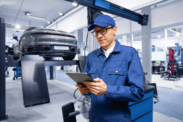 Poster - Serviceman with digital tablet on the background of the car in the car service.