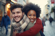 Young man giving piggyback ride to African woman. Happy couple in sweaters and scarves looking at camera. Winter fun in the street.