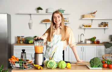 Wall Mural - Young woman making healthy smoothie with blender in kitchen