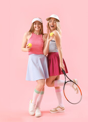 Wall Mural - Young sisters with tennis racket and balls on pink background