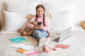 Canvas Print - Little girl with mobile phone studying computer sciences online at home