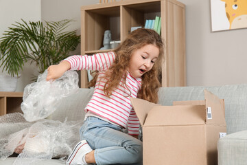 surprised little girl unpacking parcel at home
